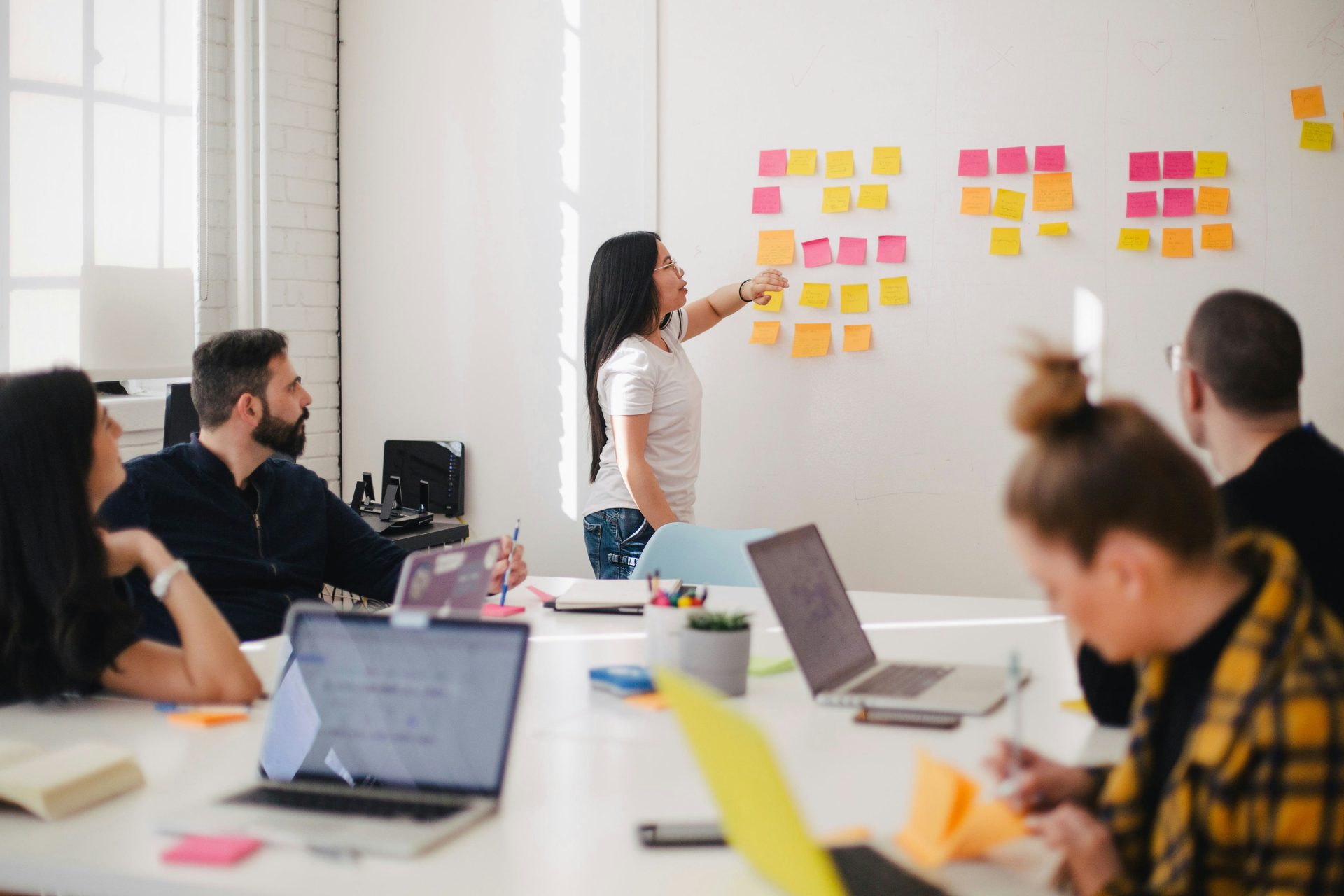 woman placing sticky notes on wall management meeting